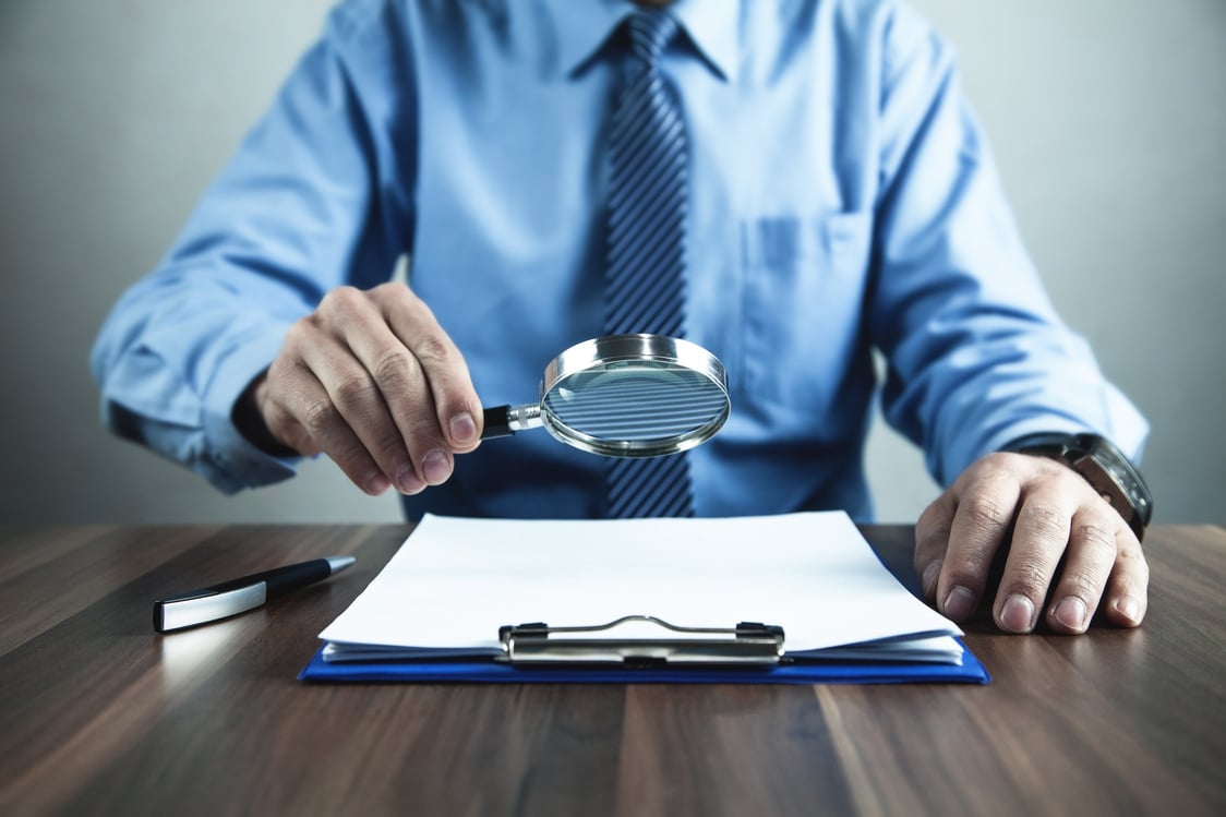 Businessman with magnifying glass reading document.